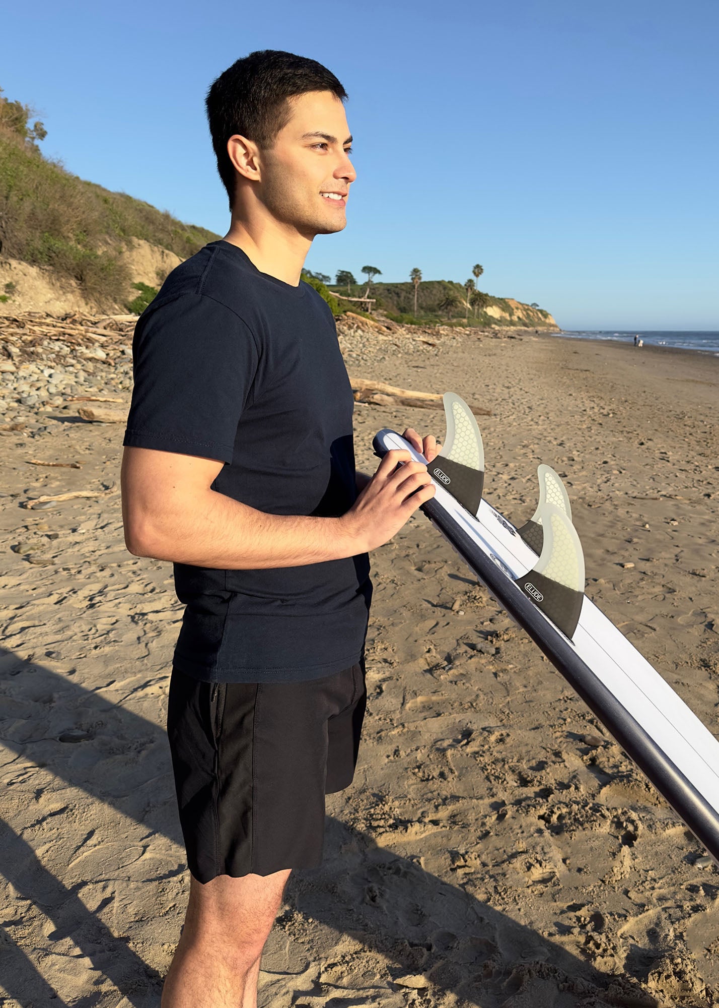Surfer holding board with fins at beach