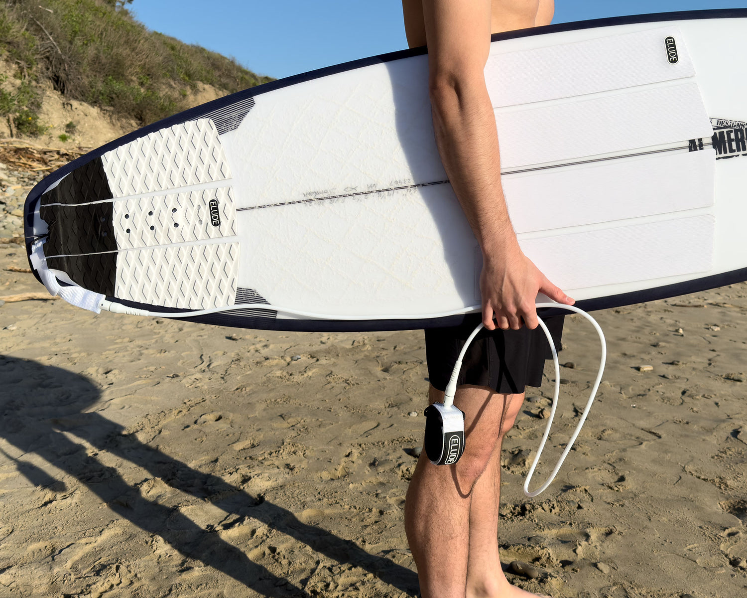 Surfer holing board with white leash and traction pads