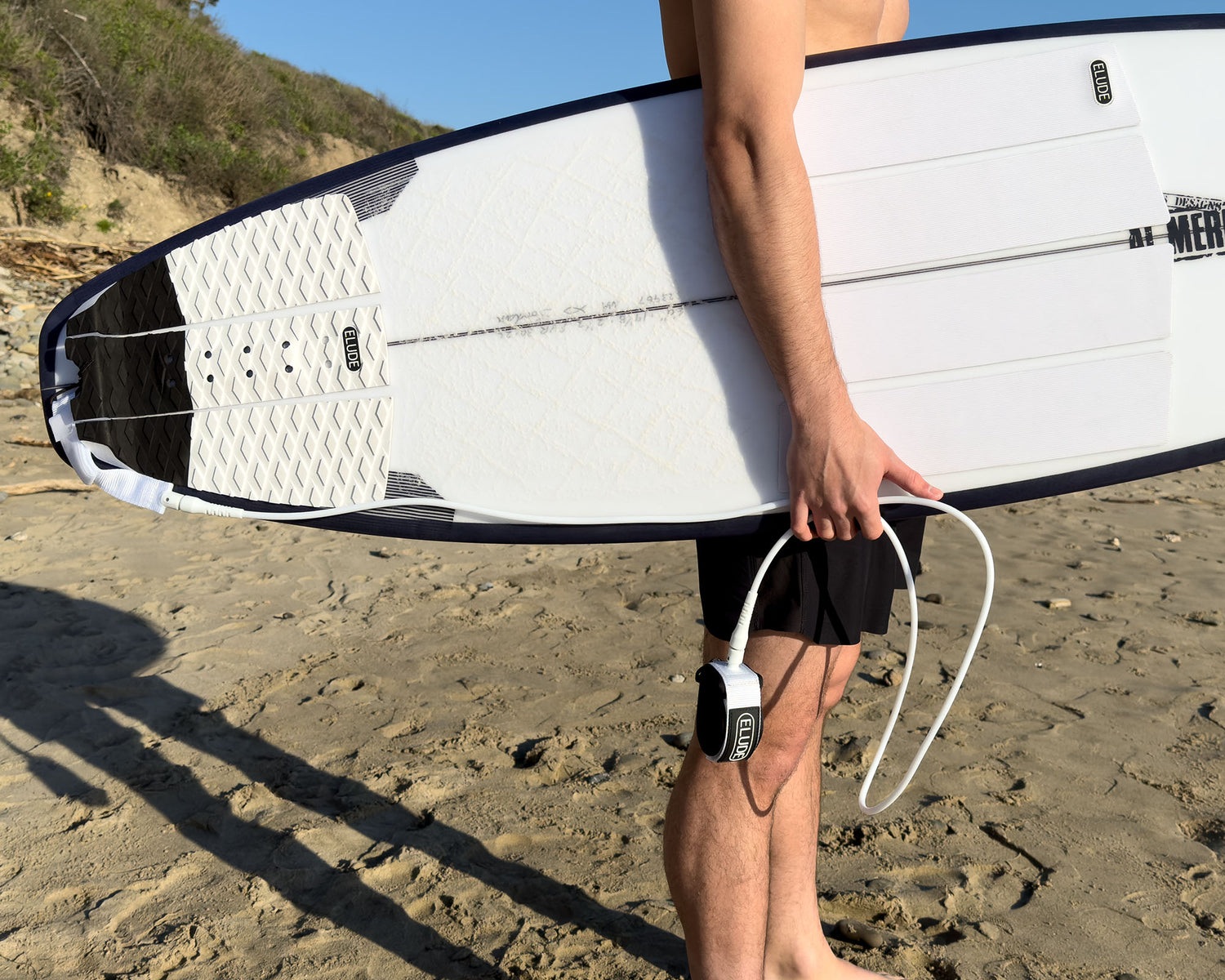 Surfer holing board with white leash and traction pads